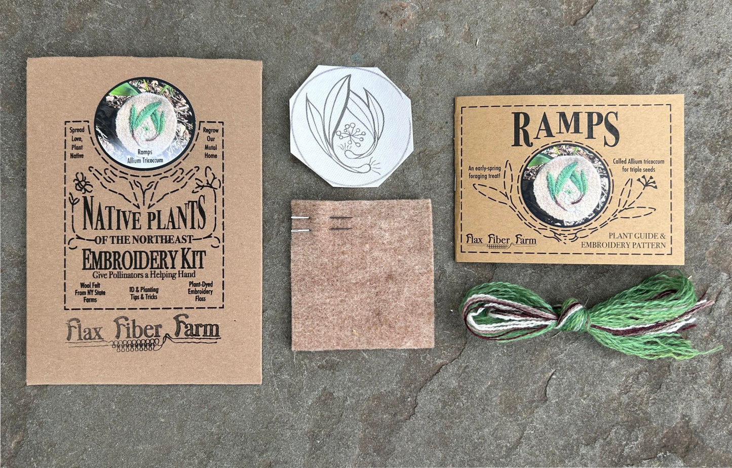 A flat-lay assortment of ramp embroidery kit components including the envelope, the wool felt and needles, the embroidery design template, the instruction booklet and the embroidery floss.